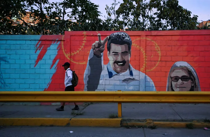 A man walks past a mural showing Venezuela's President Nicolas Maduro and his wife Cilia Flores, after US President Donald Trump said on Saturday the US has struck Venezuela and captured Maduro, in Caracas, Venezuela January 3, 2026 (credit: REUTERS/Maxwell Briceno)